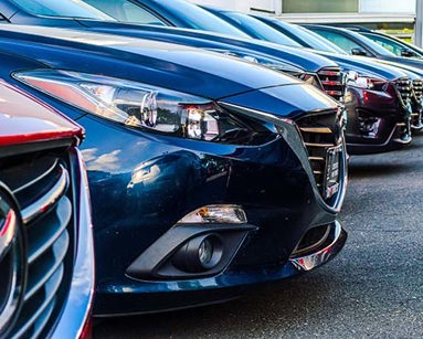 A row of cars, parked in a dealership forecourt.