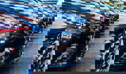 A row of cars, parked in a dealership forecourt.