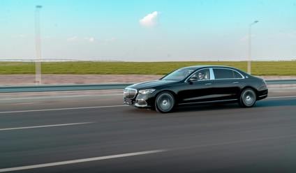 Black saloon car driving on a modern road