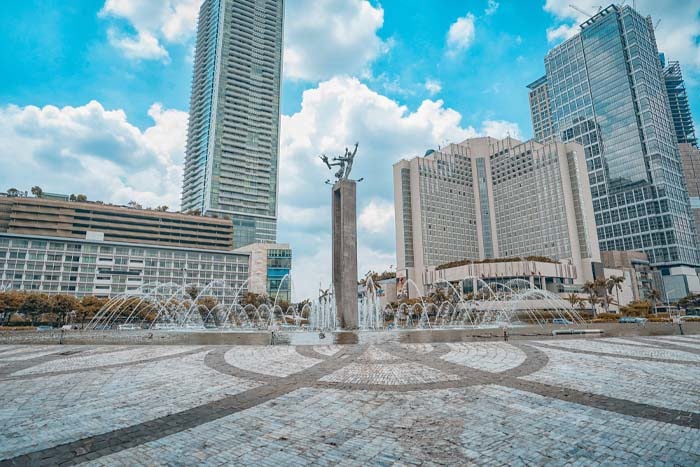 people walking on park near high rise buildings during daytime