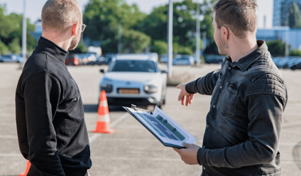 Driving instructor explaining to a student with traffic cone
