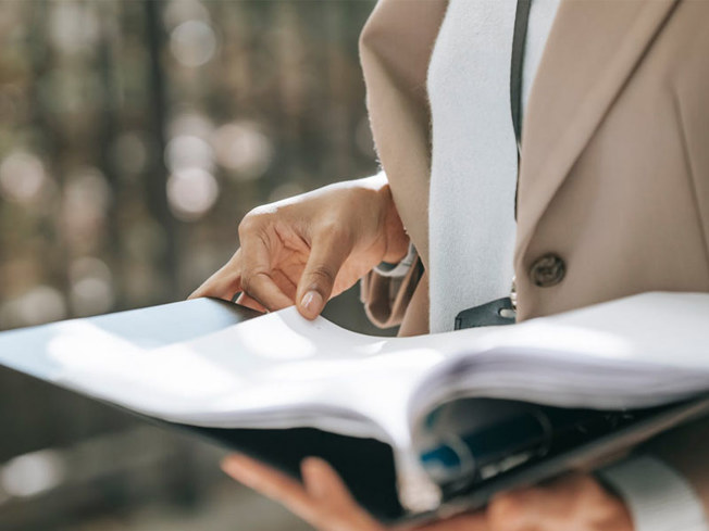 Person holding a binder full of documents