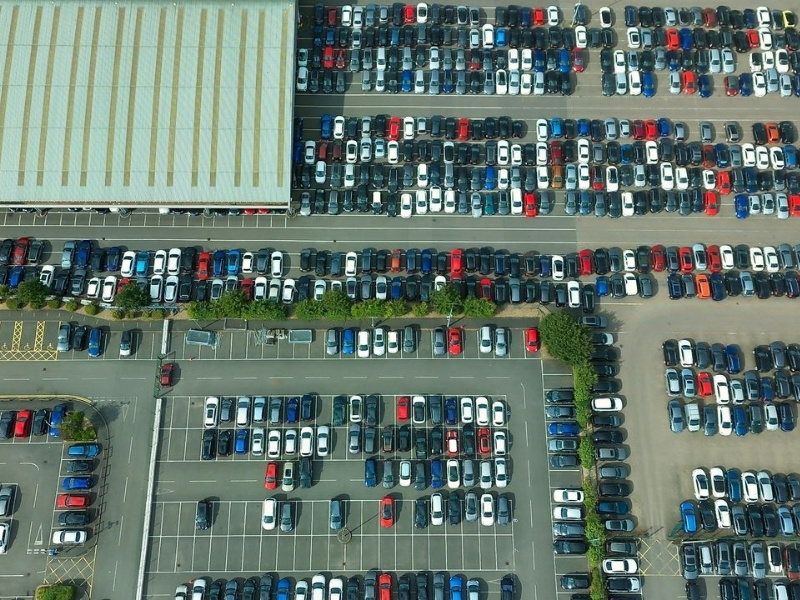 Aerial shot of a vast parking lot filled with parked vehicles and a large building.