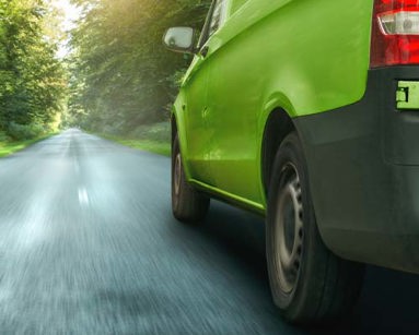 Green van on a forest road with lush vegetation