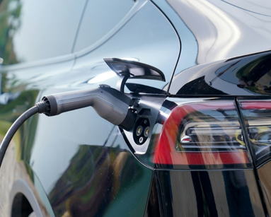 Black electric car plugged into charge