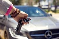 Close up of a person holding mercedes-benz car keys and pointing them towards the car