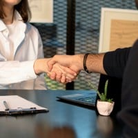 a man and a woman shaking hands in front of a laptop