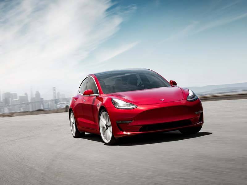 red tesla model 3 driving on open road