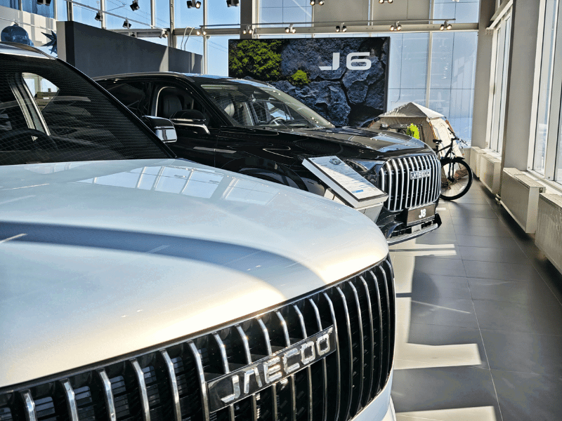 Modern car showroom features Chinese OMODA cars for sale in a bright dealership space with multiple vehicles displayed