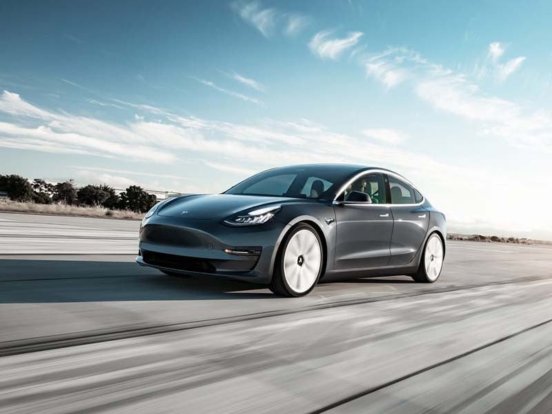 black tesla model 3 driving on the road