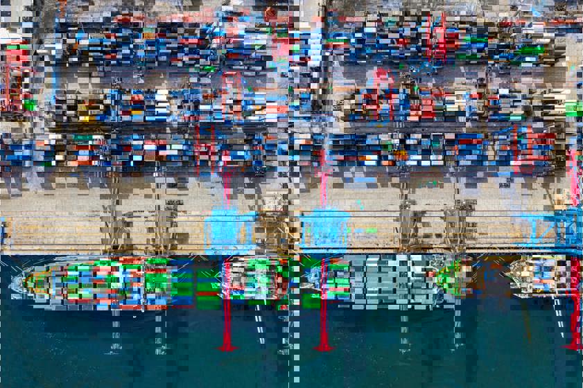 Merchant ship at a dock loading shipping containers