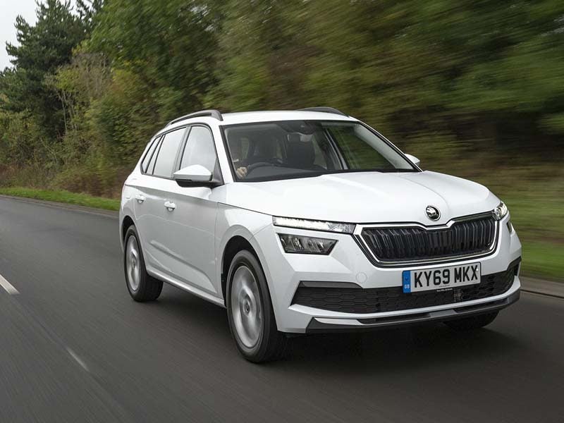 White Skoda Kamiq on a road next to trees