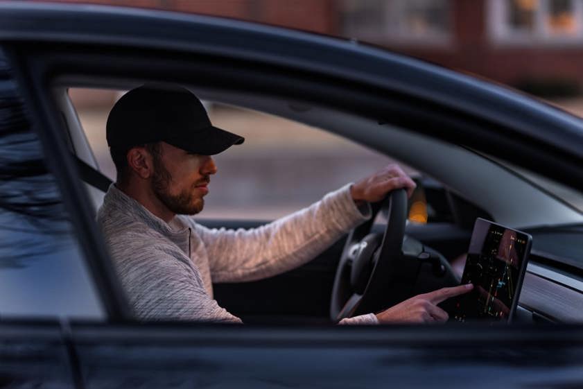 Man sitting in car using touchscreen infotainment system