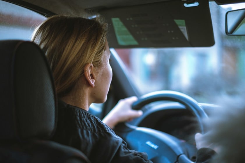 a woman sitting in a car with the steering wheel