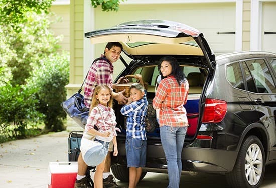 family standing at vehicle boot smiling