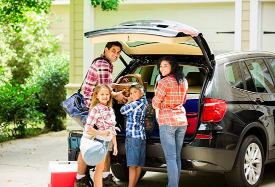 family standing at vehicle boot smiling