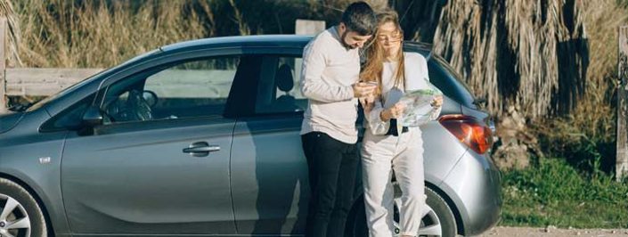 young man and woman stood next to car